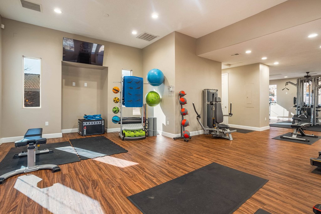 A spacious gym with a variety of equipment and a wooden floor.
